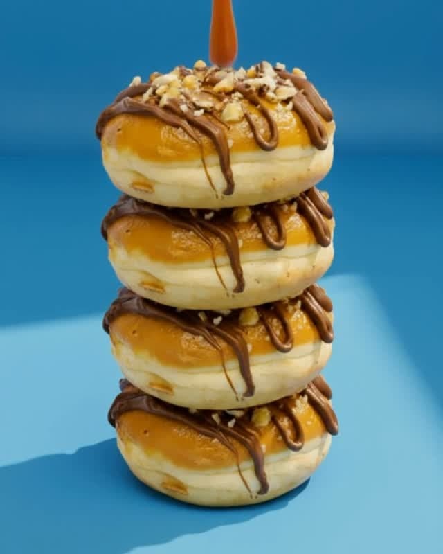 A stack of caramel donuts drizzled with chocolate